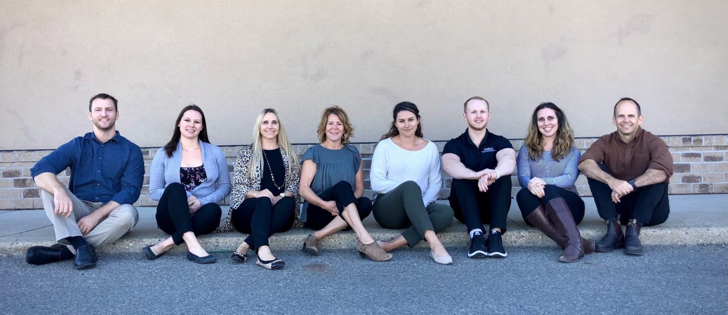team at curb b North 49 Physical Therapy team members sitting on a curb